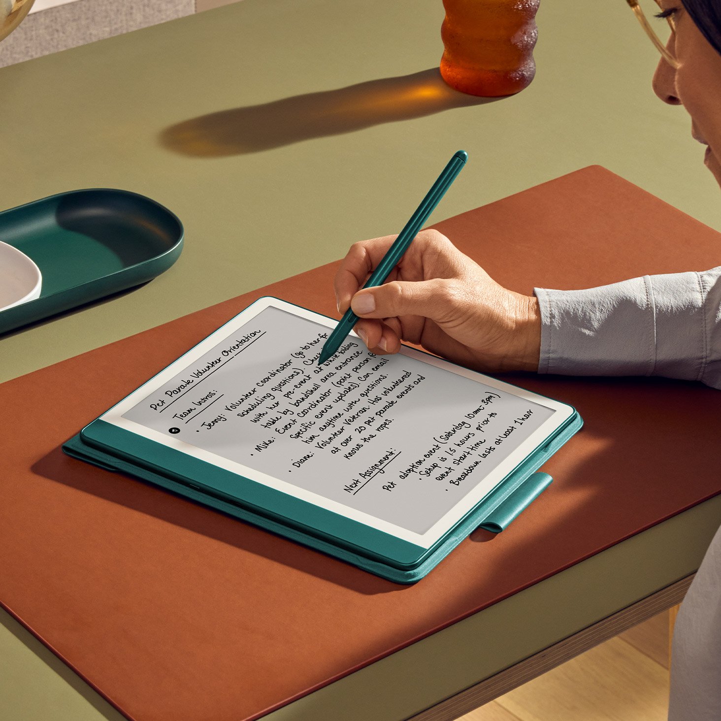 Amazon Kindle Scribe (64 GB) Kindle & Notebook in One, Includes Pen, 10.2” Display, Months of Battery Life, Metallic Jade 12 On a desk, a person writes on Kindle Scribe with a Premium Pen. On display is a page of handwritten notes.
