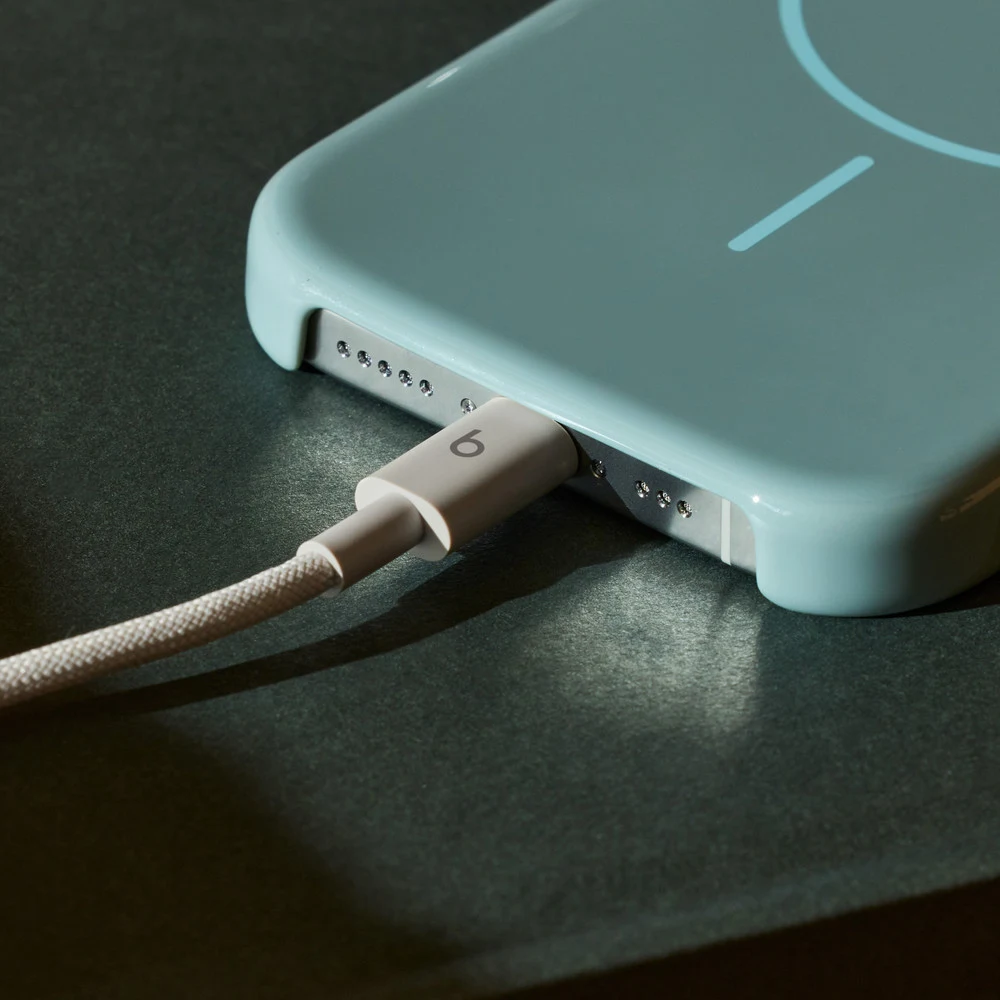 كابل Beats USB-C إلى USB-C Surge Stone – ضفيرة أوف وايت 1.5 متر، شحن سريع حتى 60 واط، بيانات USB 2.0، طرفان مقوّيان 7 كابل Beats بلون Surge Stone موصول بهاتف على مكتب